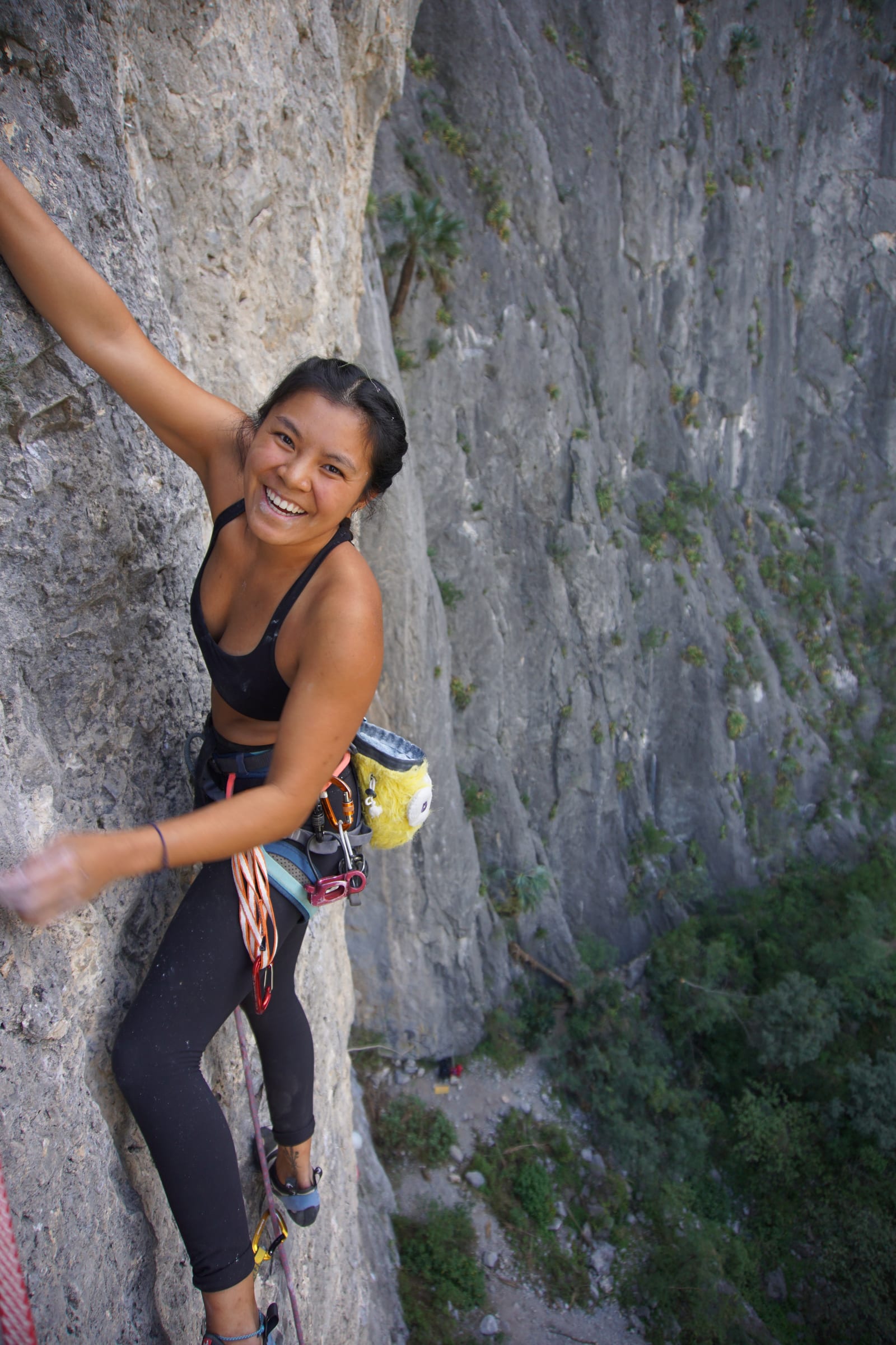 Escaladora en plena ruta, con la pared cayendo debajo