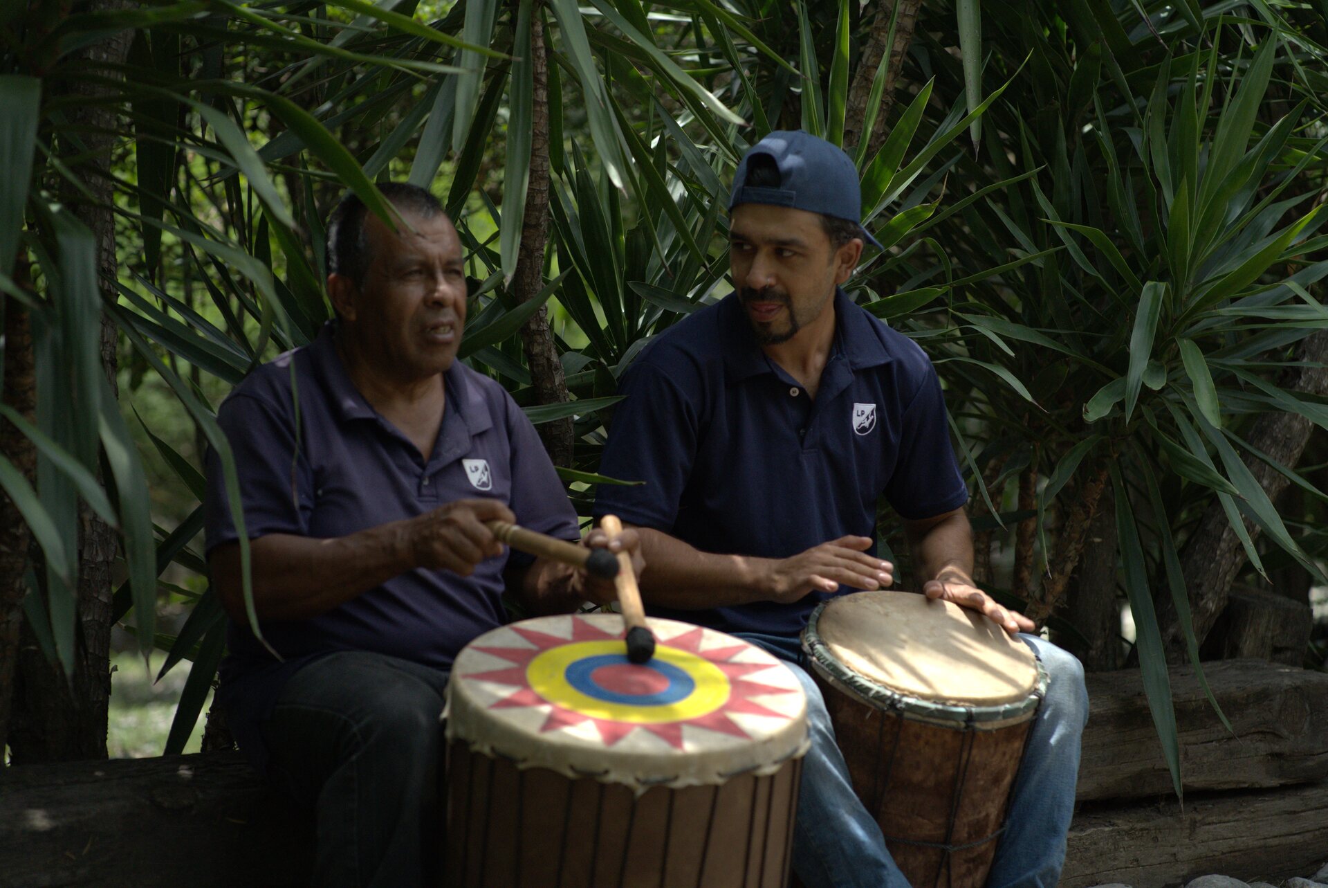 Dos músicos tocando tambores en el jardín