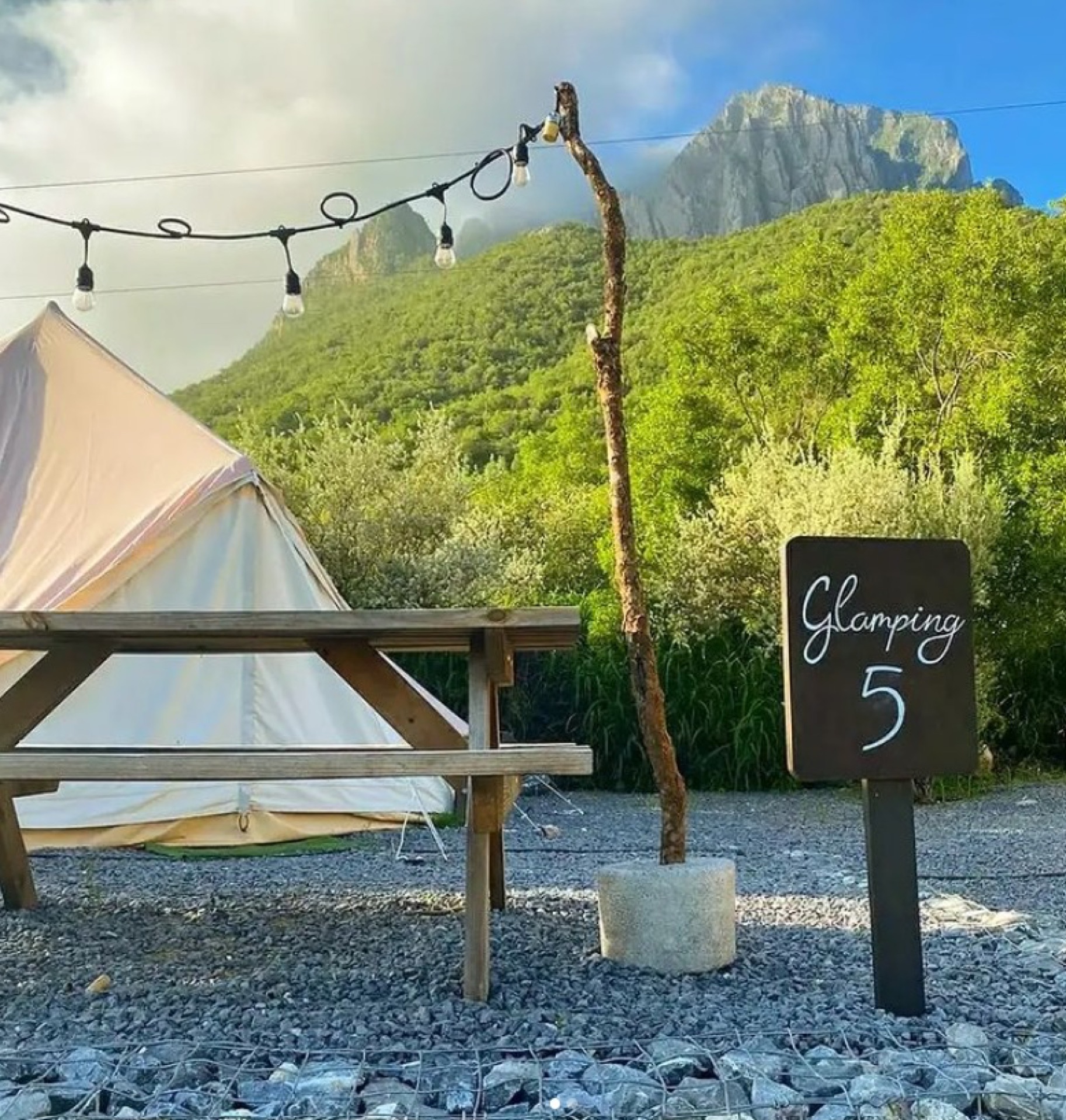 Glamping de noche con luces y la montaña detrás